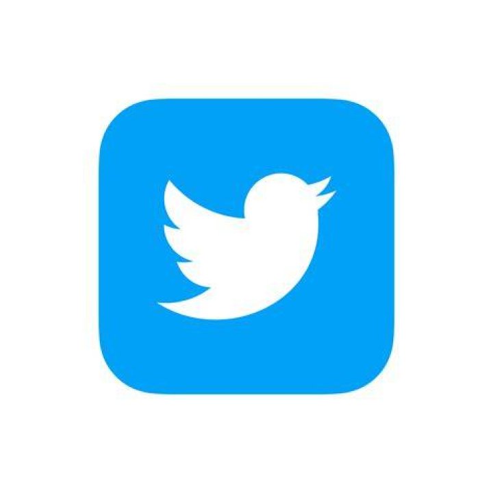 Photo of the Twitter logo on a phone over a laptop keyboard.