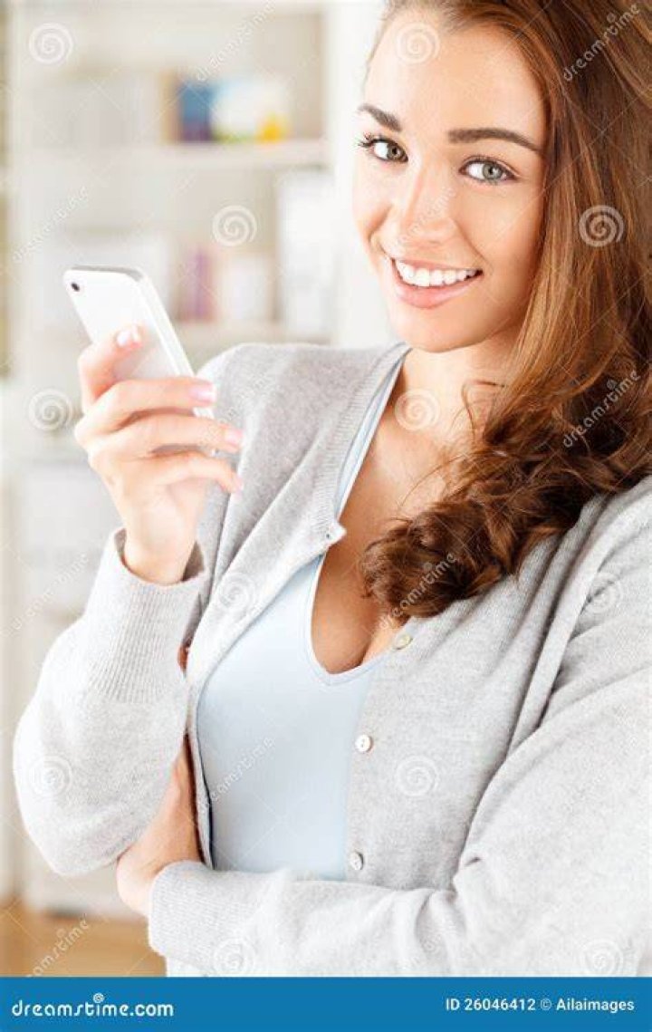 Young woman using mobile phone sending sms or texting with Christmas tree in background.